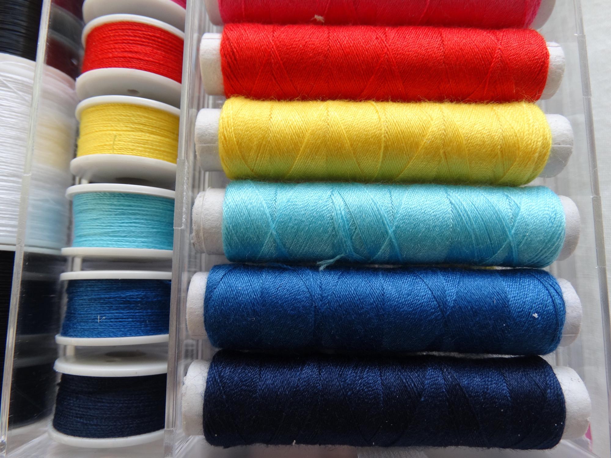 Rolled fabric and spools of thread next to embroidery sample